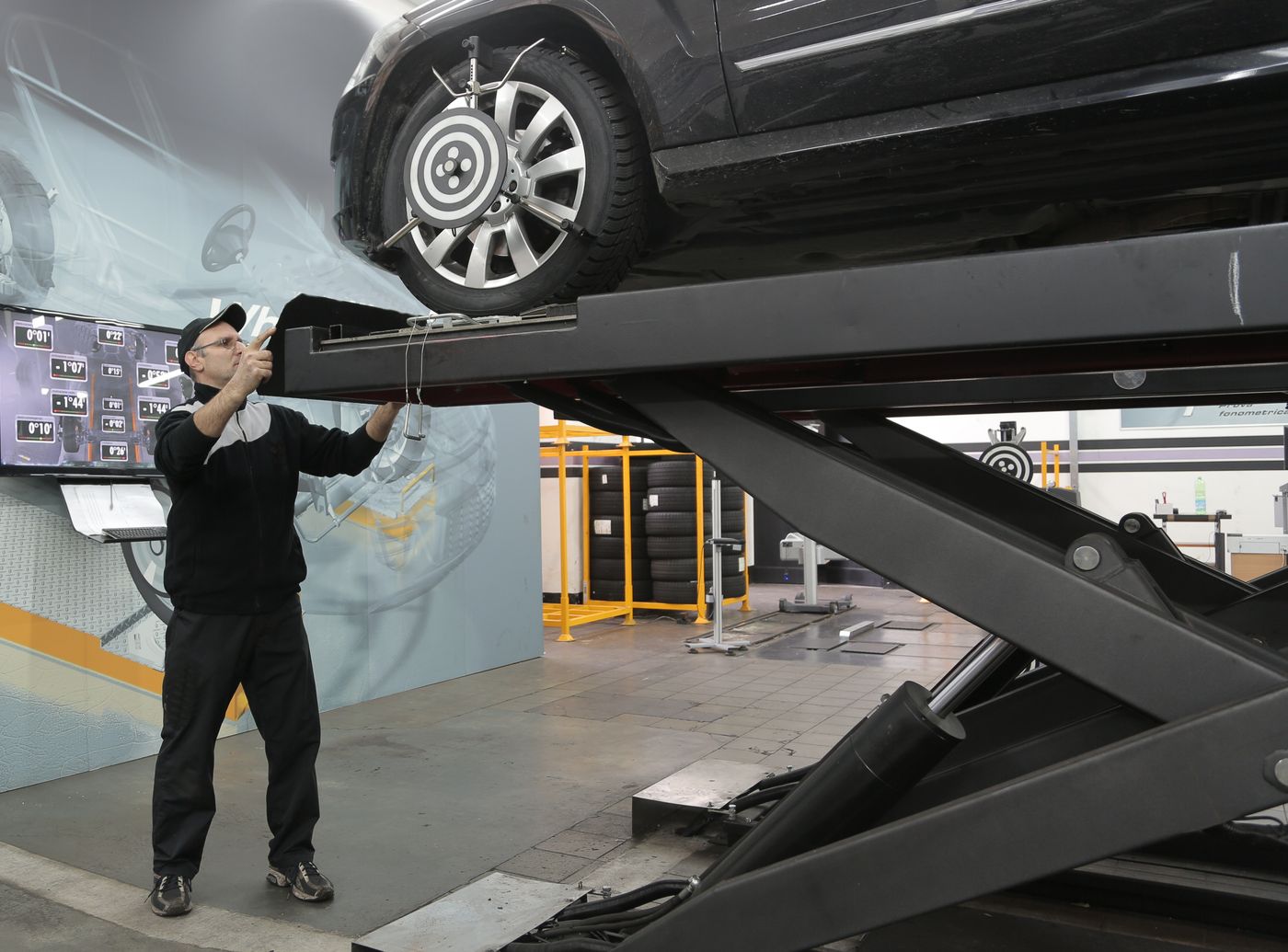 Technician aligning wheels on a hoist